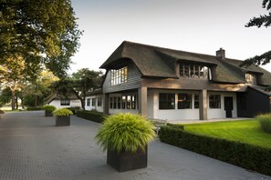 A modern house with a thatched roof, large windows, and a paved driveway. - Hotel Mooirivier (Dalfsen)