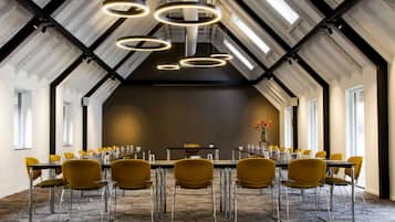 A conference room with a long table, yellow chairs, and modern pendant lighting.