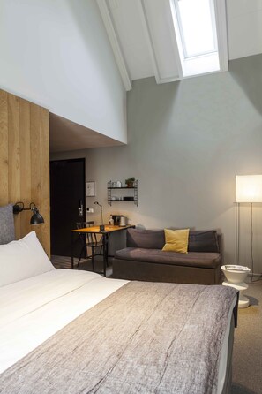 A bedroom with a bed, a desk, a sofa, and a lamp. - Hotel Mooirivier (Dalfsen)