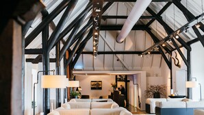 A spacious lobby with high ceilings, exposed beams, and modern lighting fixtures. - Hotel Mooirivier (Dalfsen)