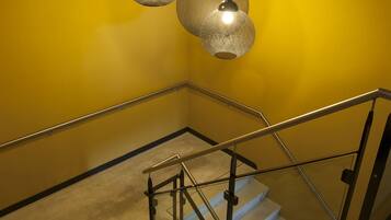 A staircase with a metal handrail and carpeted steps, leading to a landing with two hanging pendant lights.