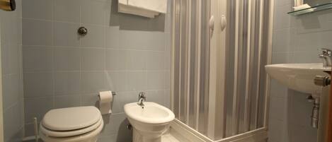 Un baño con inodoro, bidé y ducha.
