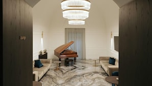 A lounge with a grand piano, marble flooring, and a chandelier. - Albergo Italia (Matera)