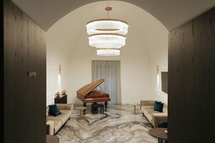 Una sala da conversazione con un pianoforte a coda, pavimento in marmo e un lampadario.