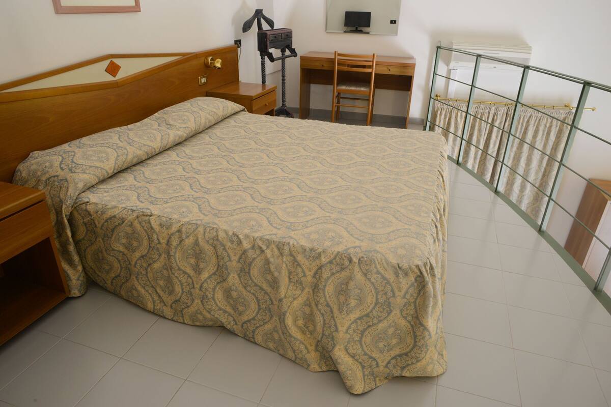 Un dormitorio con una cama de madera, un escritorio y una silla.