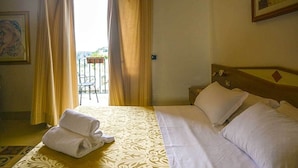 A hotel room with a bed, a nightstand, and a view of the outdoors. - Albergo Italia (Matera)