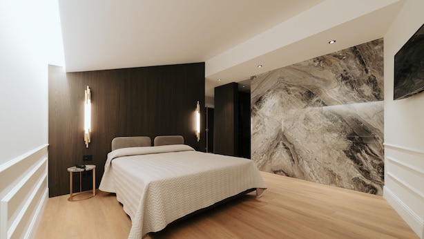 A modern bedroom with a large bed, a marble wall, and a minimalist design. - Albergo Italia (Matera)