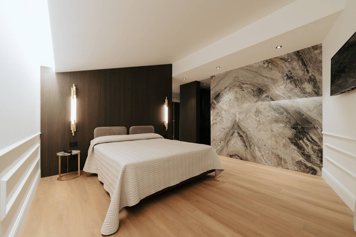 Un dormitorio moderno con una cama grande, una pared de mármol y un diseño minimalista.