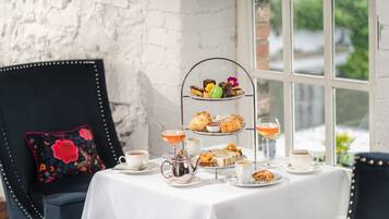 A table set with tea, pastries, and a tiered dessert stand.