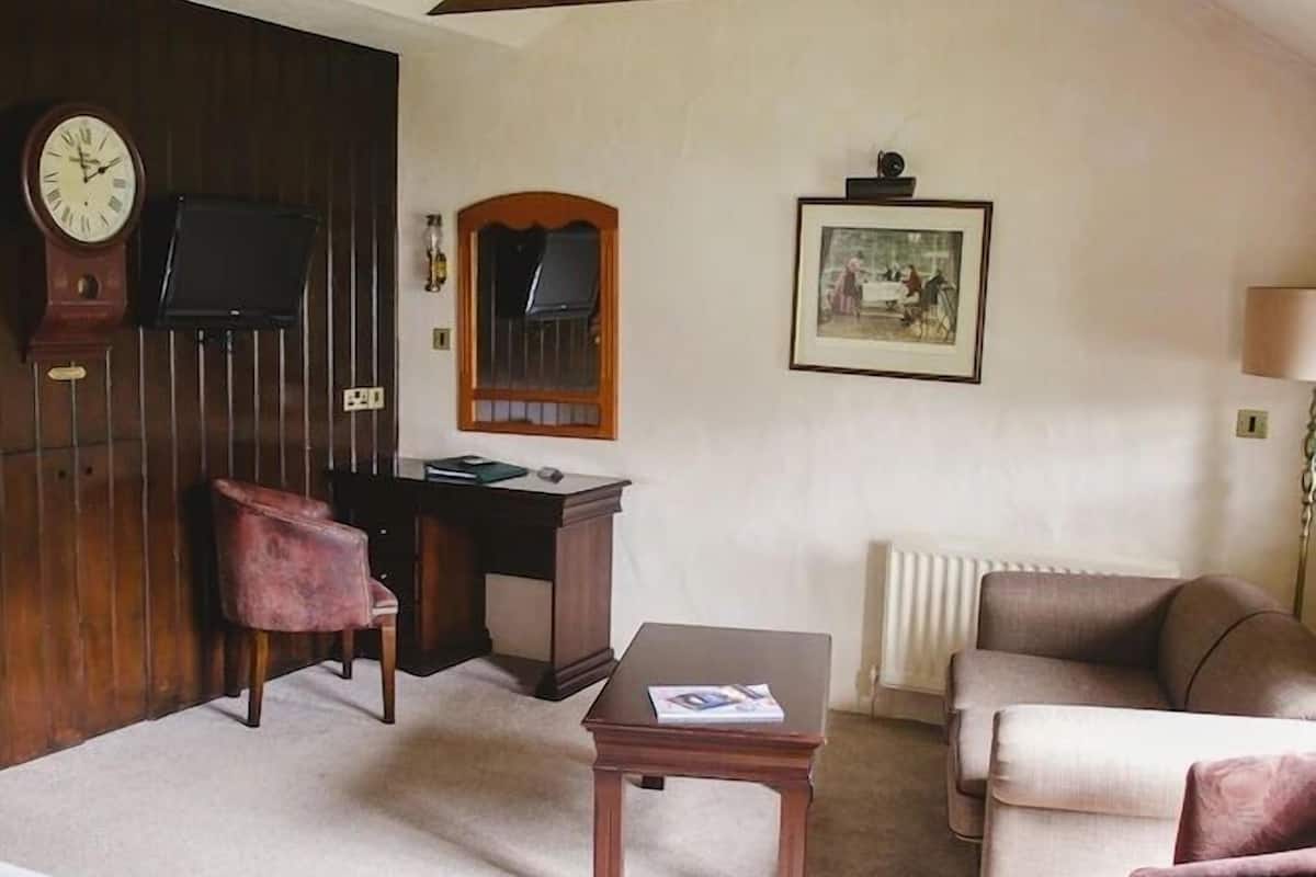 Une pièce comprenant un lit, un bureau, une chaise, un radiateur et une horloge murale.