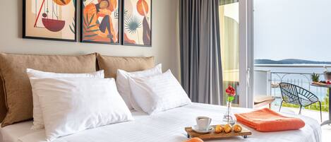 Ein Hotelzimmer mit Bett, weißen Kissen, Tablett mit orangenen Handtüchern, einer Kaffeetasse und einer Vase mit einer Blume.