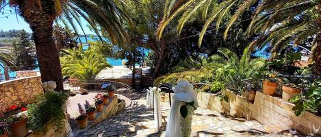 Una escalera de piedra que conduce a una terraza con plantas en macetas y vistas al mar.