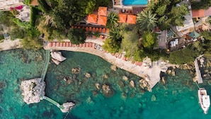 Vista aérea de una propiedad costera con piscina, zona de estar y costa rocosa.