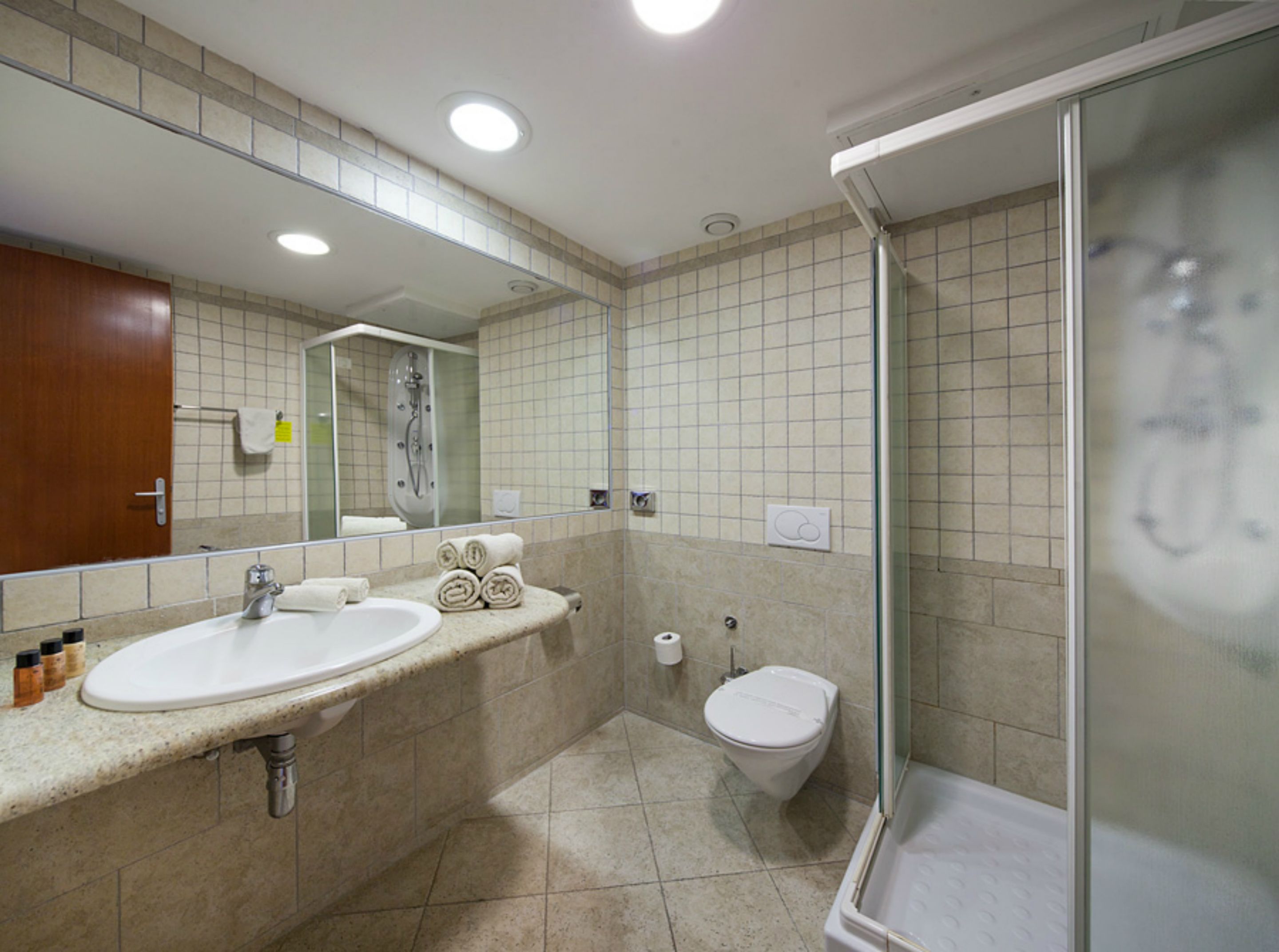 Un baño moderno con lavamanos, espejo y ducha.