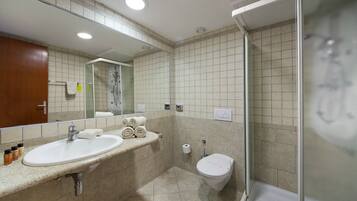 Un baño moderno con lavamanos, espejo y ducha.