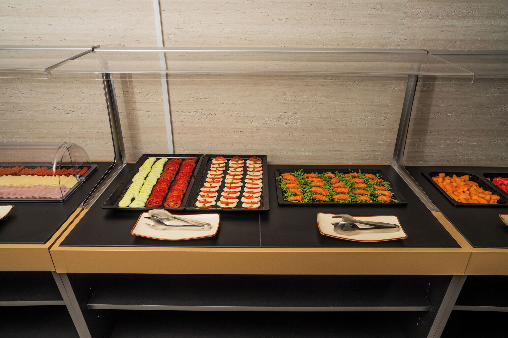A buffet with various food items, including sushi, vegetables, and meats, arranged on trays.