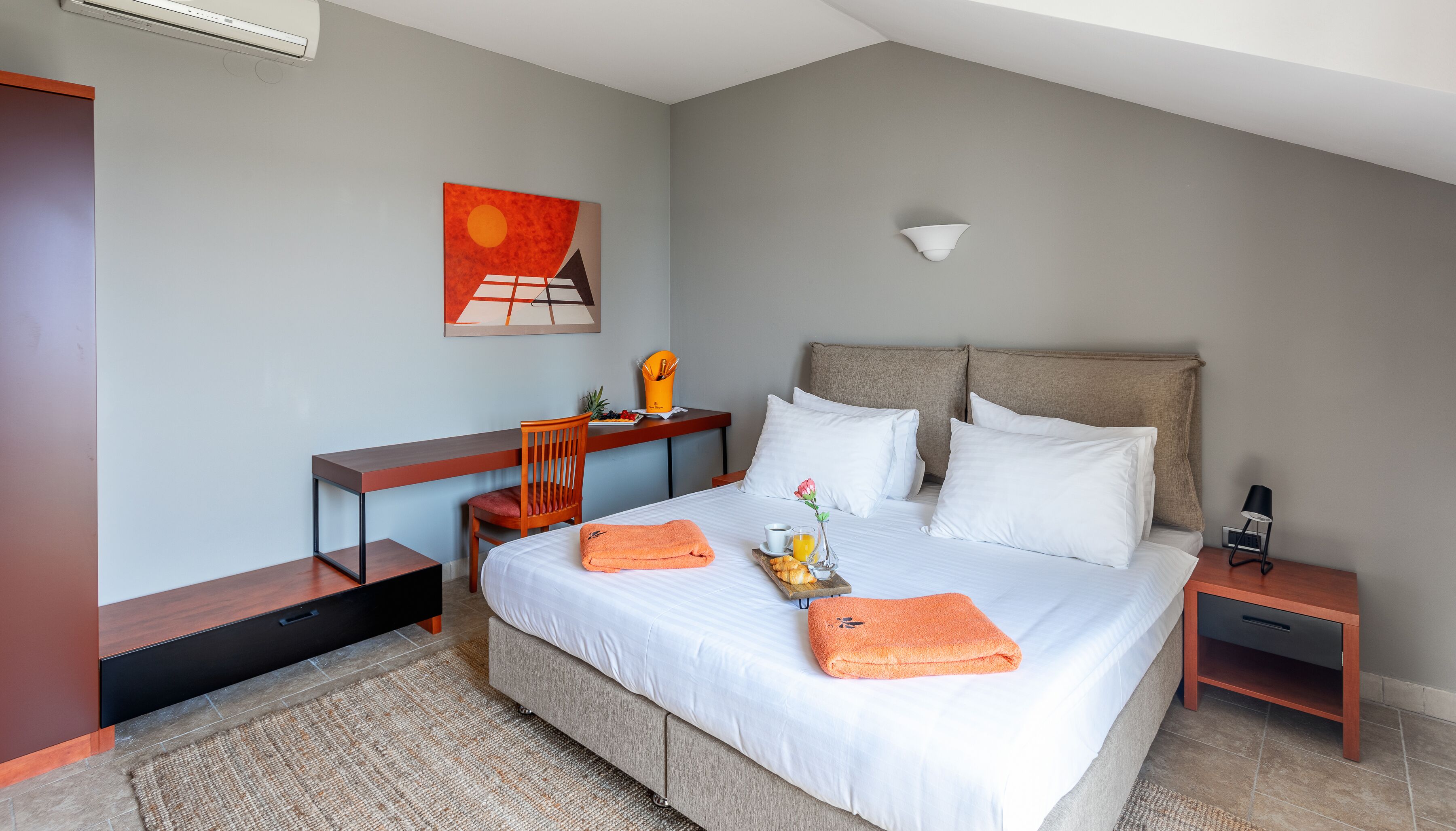 Ein Hotelzimmer mit Bett, Nachttisch, Stuhl, Schreibtisch und einem Bild an der Wand.