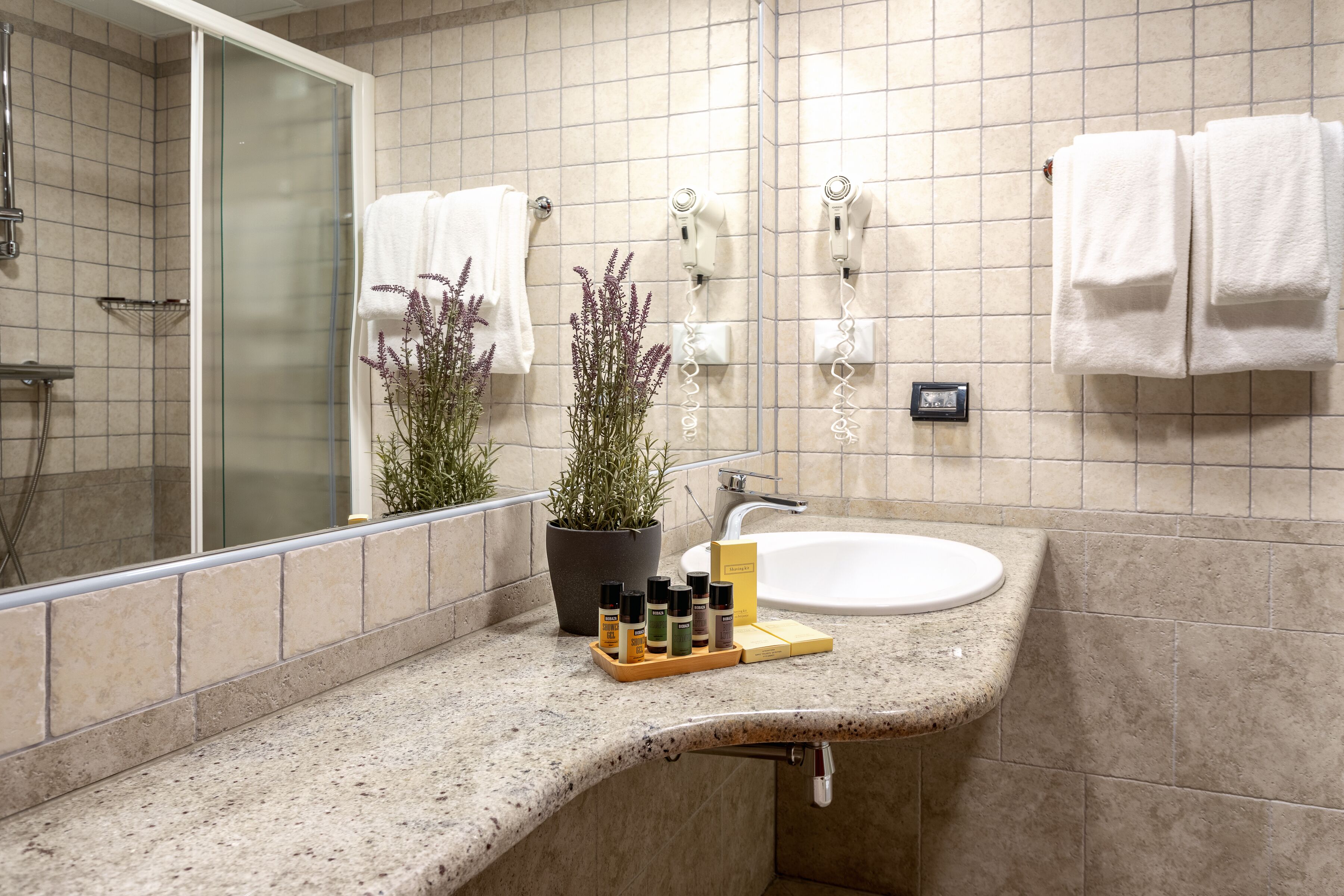 A bathroom with a sink, mirror, towel rack, and a potted plant.