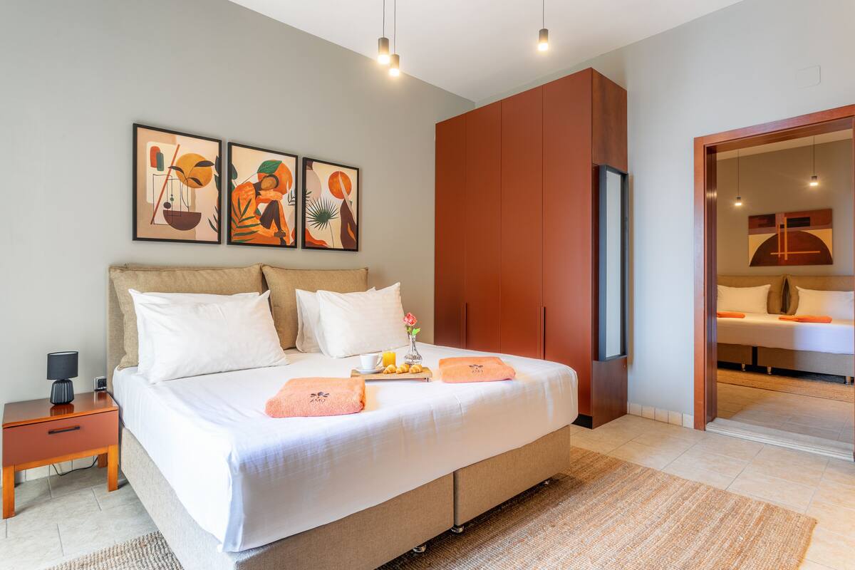 A modern bedroom with a large bed, a nightstand, a wardrobe, and artwork on the wall.