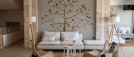 A modern living room with a sofa, two side tables, a coffee table, and woven floor seating.