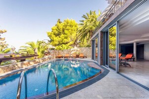 Una piscina al aire libre, sillones reclinables de piscina