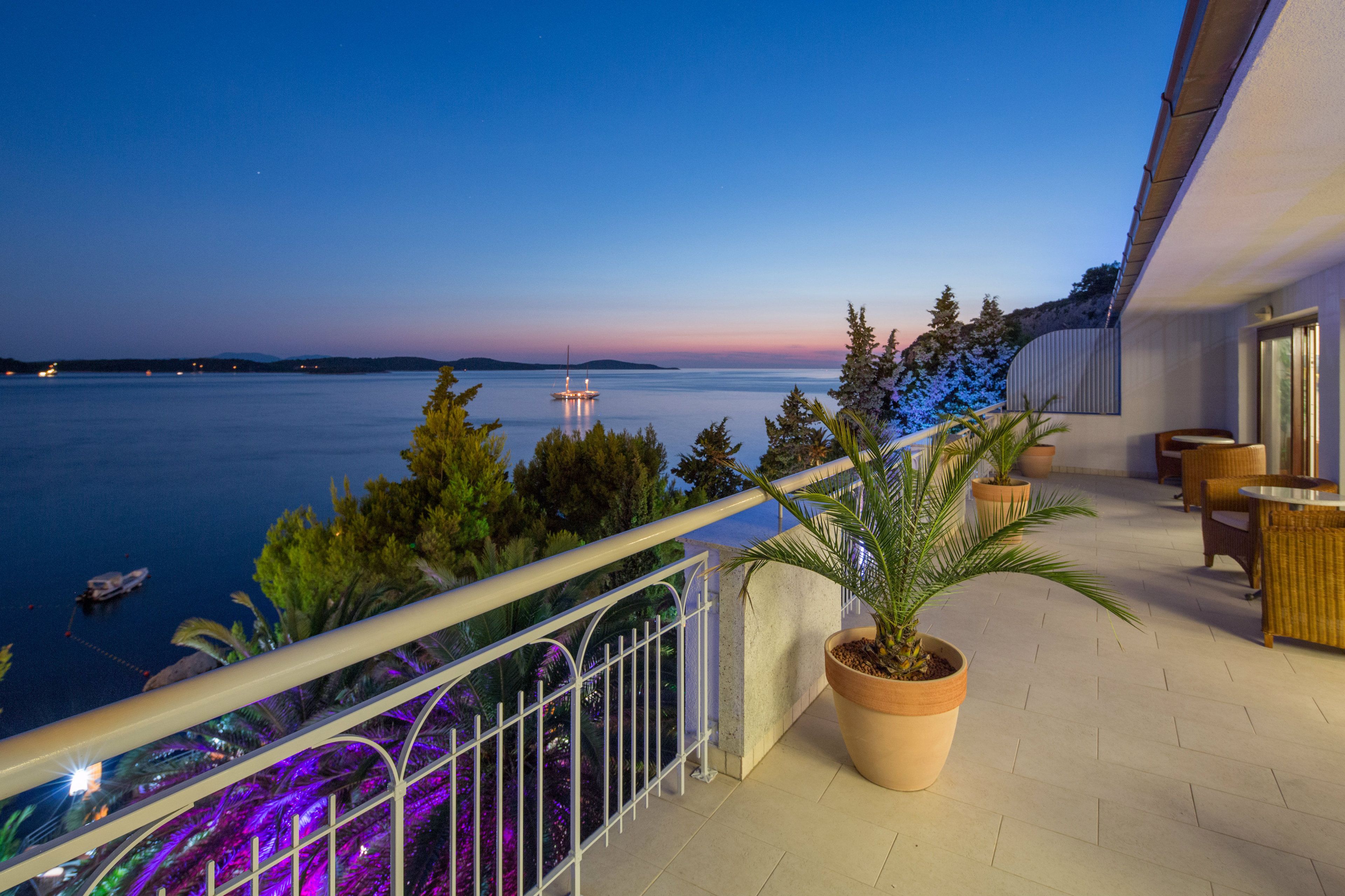 Un balcon avec vue sur la mer, des plantes en pot et du mobilier d’extérieur.
