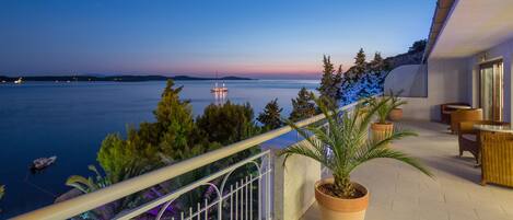 Un balcon avec vue sur la mer, des plantes en pot et du mobilier d’extérieur.