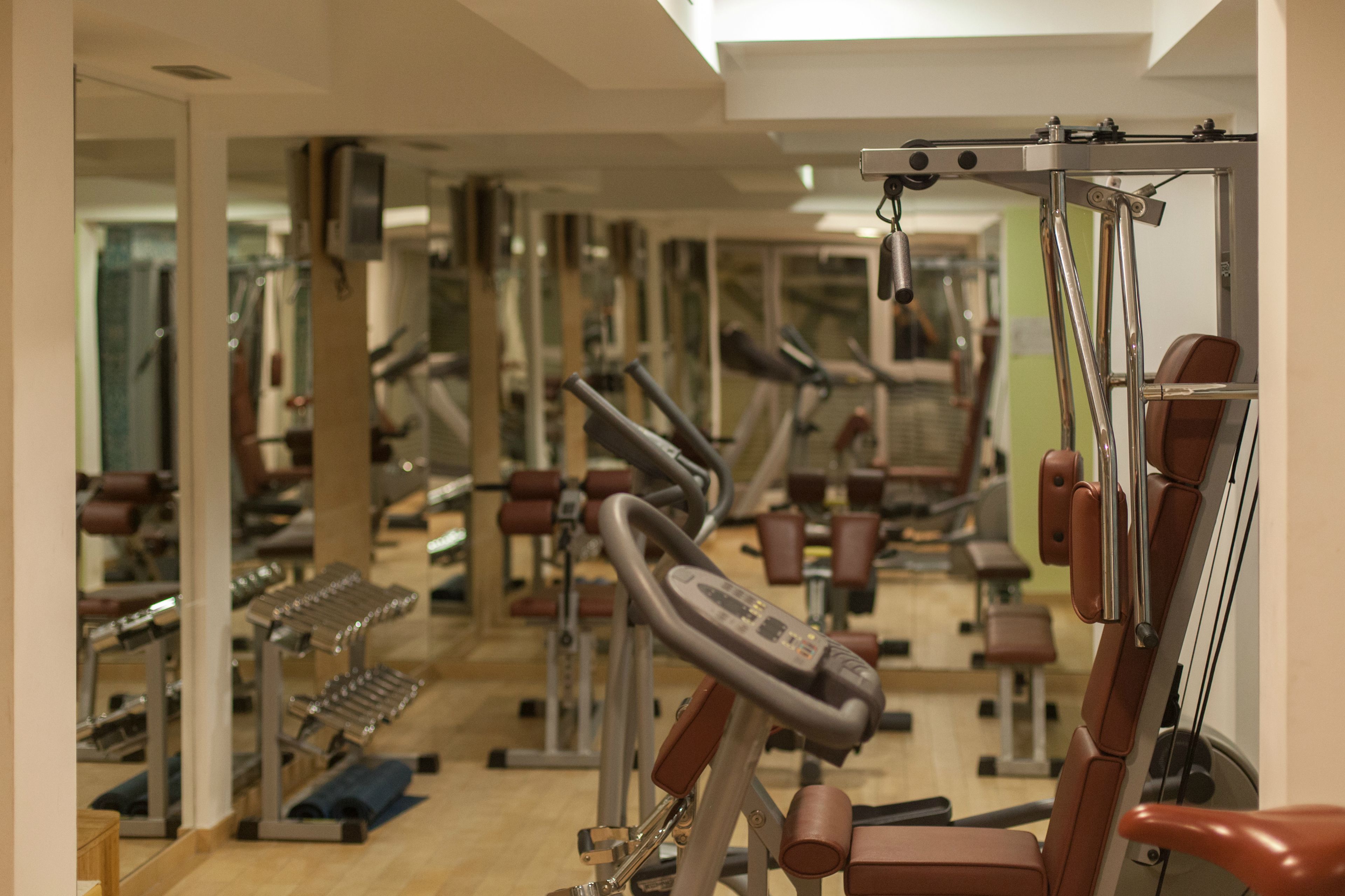 Une salle de sport équipée de divers appareils d’exercice et dont les murs sont recouverts de miroirs.