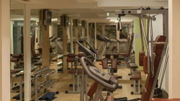 Un gimnasio con varias máquinas de ejercicio y espejos en las paredes.