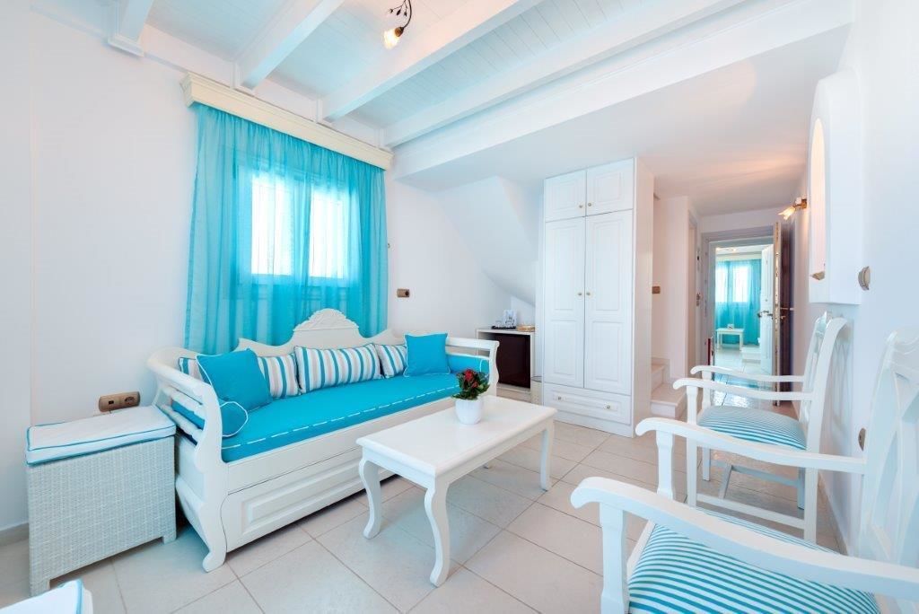 A bright, white room with a blue-striped sofa, a white coffee table, and white chairs.