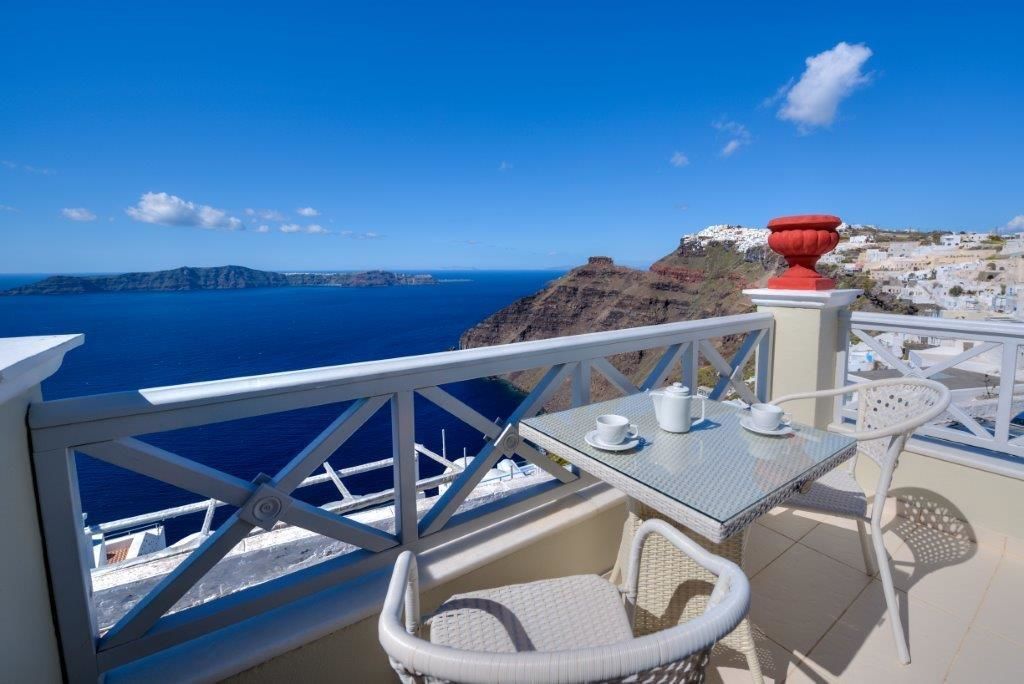 Ein Balkon mit Blick auf das Meer und ein weißes Gebäude in der Ferne.