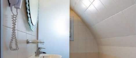 A compact bathroom with a white sink, a toilet, and a shower area.