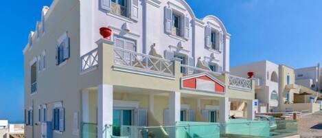 Un bâtiment à deux étages doté de balcons, d’une piscine et surplombant un ciel d’un bleu limpide.