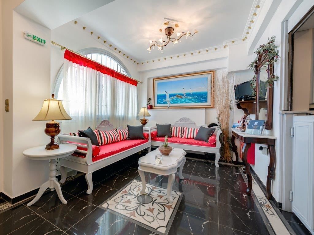 A living room with a white sofa set, a coffee table, a painting of seagulls, and a chandelier.