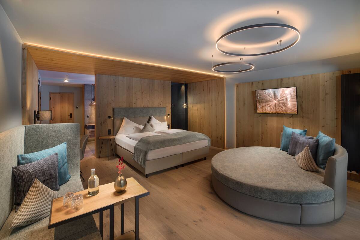 A modern bedroom with a bed, two sofas, a small table, and a TV.
