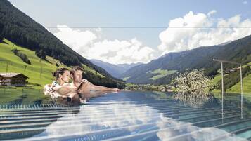 Ein Paar in einem Pool mit Glasboden und Blick auf die Berge.