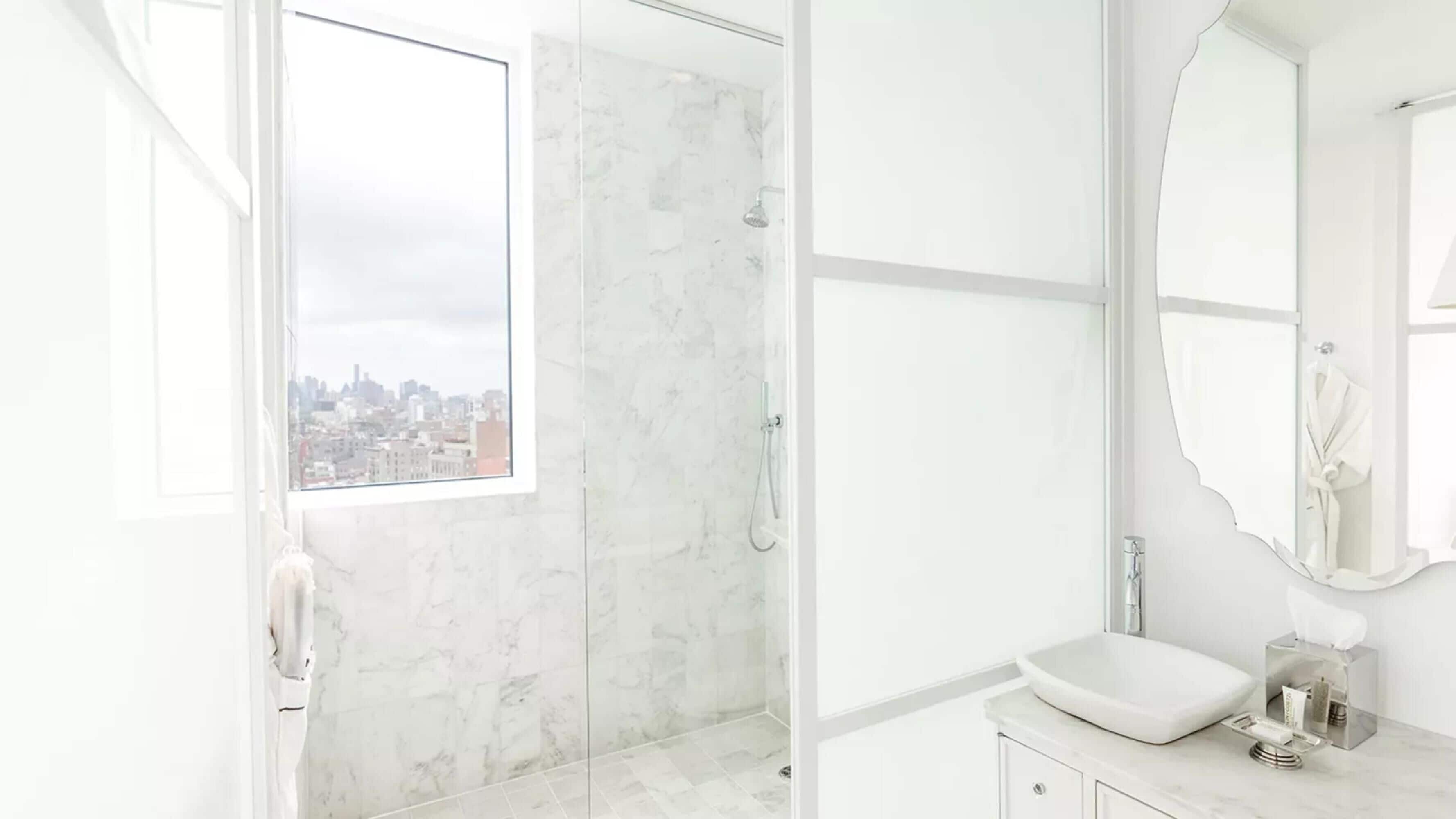 Ein modernes Badezimmer mit großem Fenster, einer bodengleichen Dusche und einem weißen Waschbecken.