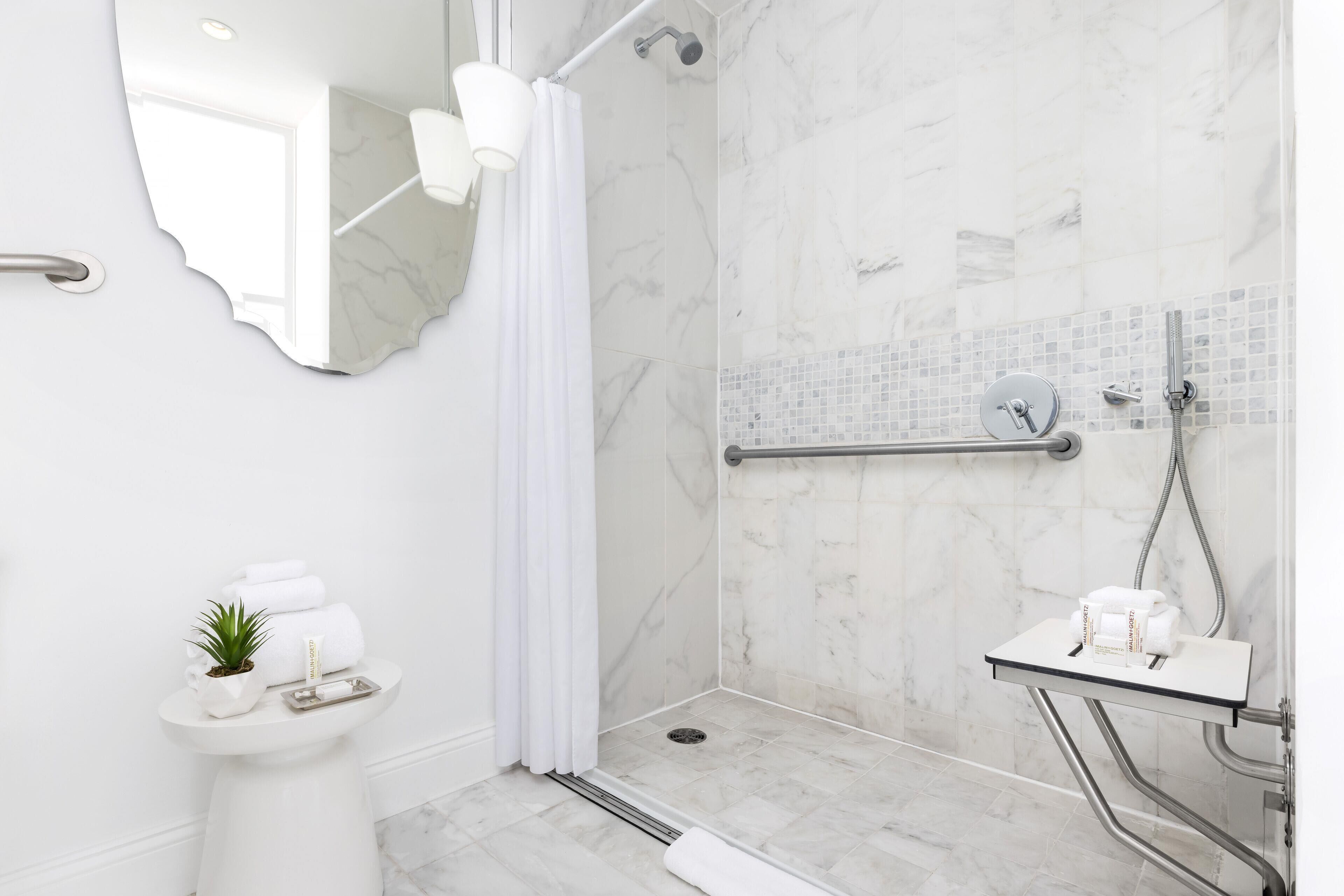 A modern bathroom with a shower, a sink, and a mirror.