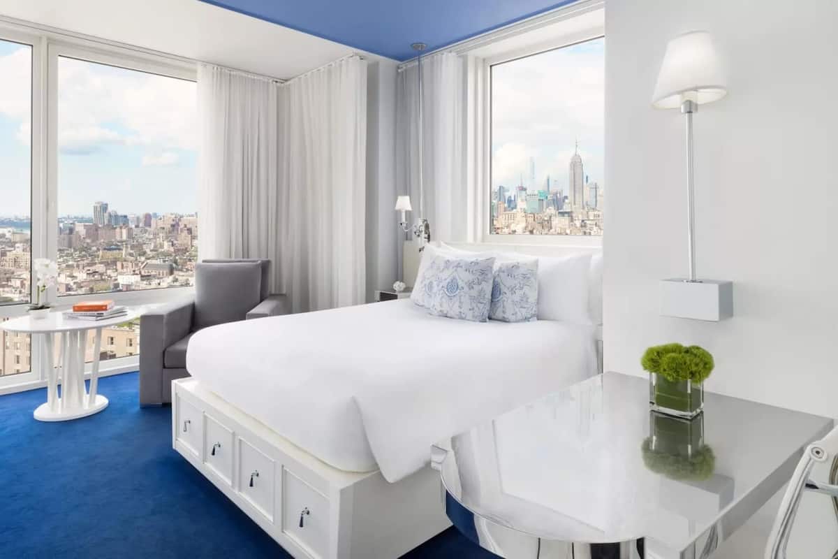 Une chambre d’hôtel avec un grand lit, un bureau, une chaise et une vue sur le paysage urbain.