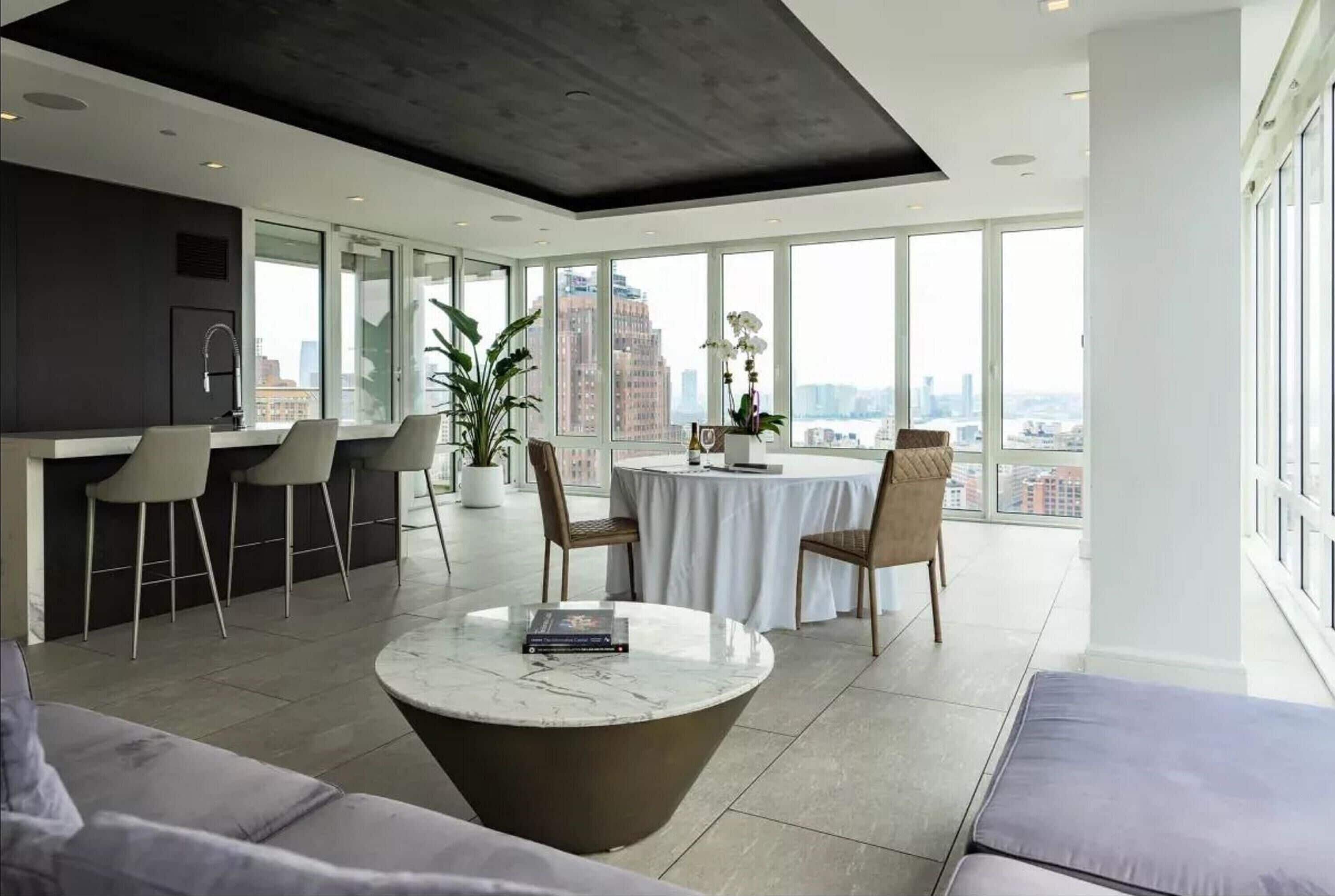 A modern kitchen with a dining area, large windows, and a city view.