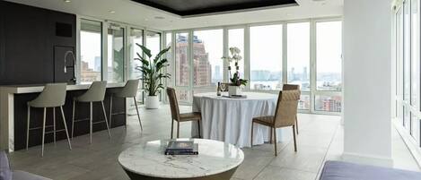 A modern kitchen with a dining area, large windows, and a city view.