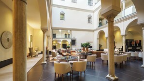 A spacious hotel lobby with multiple seating areas, large columns, and a high ceiling. - Eurostars Sevilla Boutique (Seville)