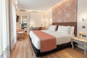 A hotel room with a large bed, bedside tables, a desk, and a chair.