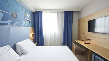 Une chambre d’hôtel avec un lit, un bureau, une télévision et une fenêtre avec des rideaux.