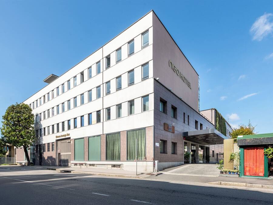 A modern hotel with a flat facade, large windows, and a green awning.