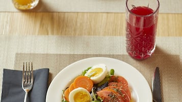 Una mesa con dos platos de comida, un vaso de jugo de naranja y un vaso de bebida roja.