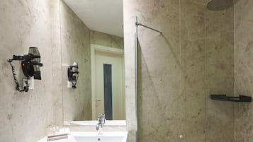 Een moderne badkamer met een grote spiegel, een wastafel, een toilet en een douche met glazen wanden.
