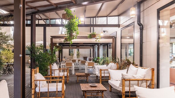 Un espacio al aire libre con mobiliario de bambú y plantas colgantes.