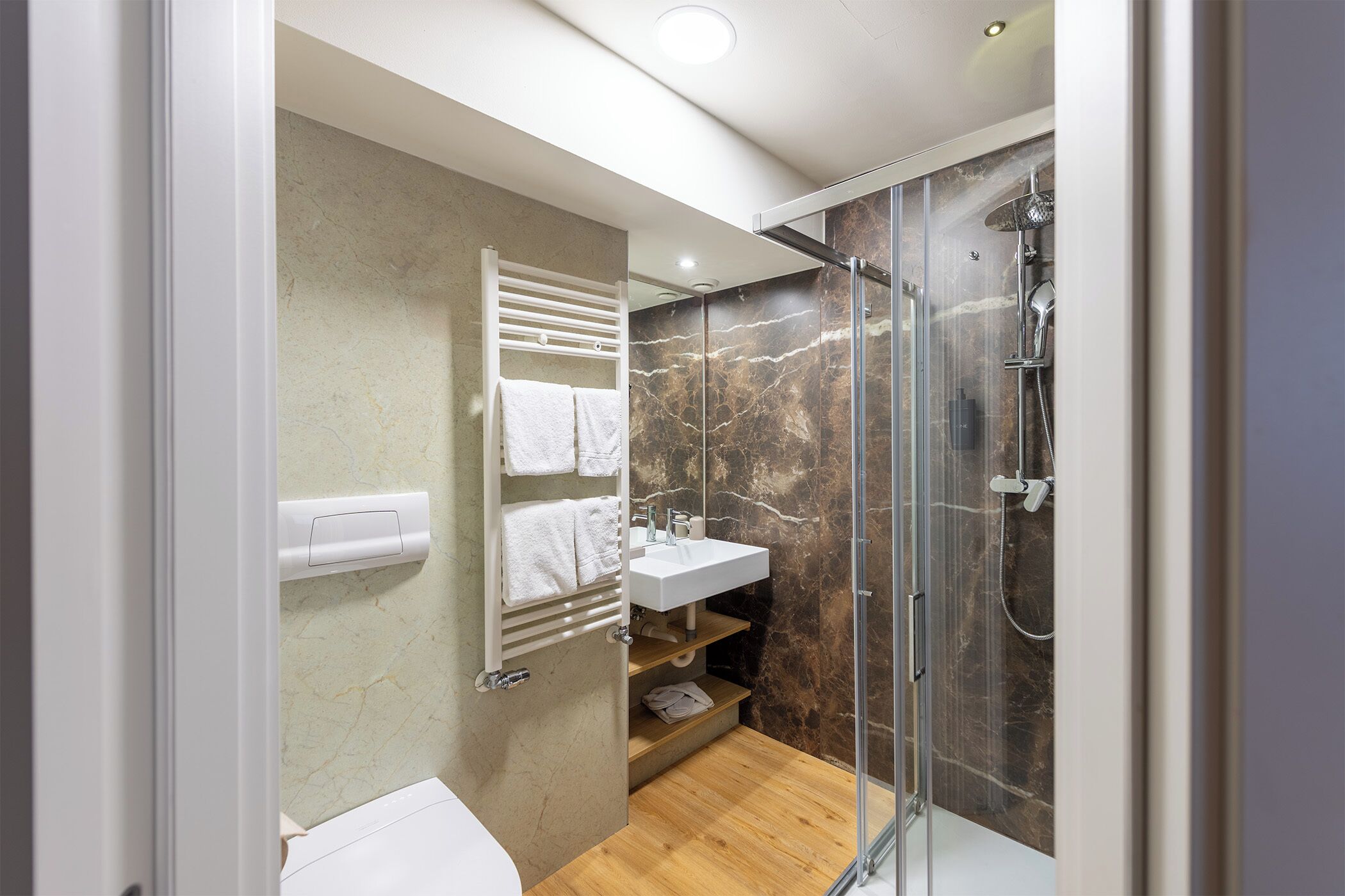A modern bathroom with a glass-enclosed shower, a white sink, and a towel rack.
