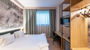 A hotel room with a bed, a desk, a television, and a wardrobe.